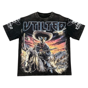 Vtilted "WILDWEST" oversized graphic tee in Heavy Black Wash — a skeleton outlaw on horseback charging across the plains at sunset, captioned "NEVER RAINS ON US"